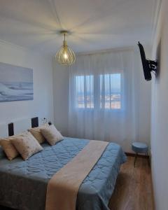 a bedroom with a bed with a blue blanket and a window at Apartamento Faro Burela in Burela de Cabo