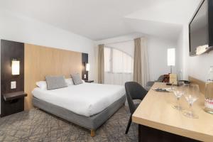 a hotel room with a bed and a table with wine glasses at H&ocirc;tel Eliseo in Lourdes