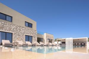 a swimming pool with lounge chairs in front of a building at Elia Villa, with Pool, SeaViews & Iconic Design, By ThinkVilla in Astérion