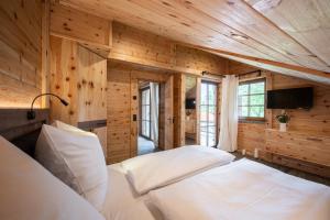 two beds in a room with wooden walls at Alpenloft Allgäu in Oy-Mittelberg