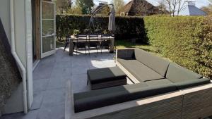 a patio with a couch and a table next to a house at OUD Duynvallei in Schoorl