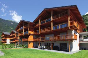 un grand bâtiment en bois avec une pelouse devant lui dans l'établissement Les Fleurettes, au Châble