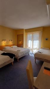 a hotel room with two beds and a window at Cit Hotel Noemys Gradignan - ex Le Chalet Lyrique in Gradignan