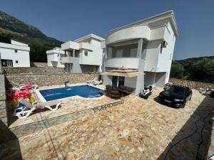a large white house with a swimming pool and a car at Villa SA in Ravanj