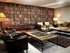 a living room with leather furniture and a large library at Finca Shenonkop Hotel Rural in Navalmoral de la Mata