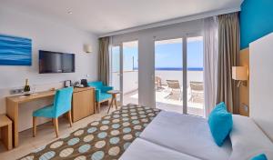a hotel room with a bed and a desk and a balcony at Universal Hotel Marqués in Colònia de Sant Jordi