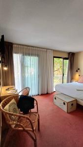 a bedroom with a bed and a table and a chair at Cit Hotel Noemys Gradignan - ex Le Chalet Lyrique in Gradignan