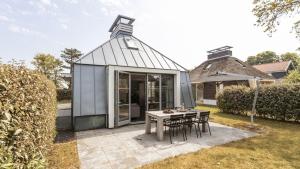 a glass house with a table and chairs at OUD Duynvallei in Schoorl
