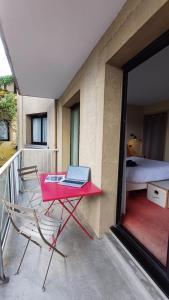 a red table with a laptop on top of a balcony at Cit Hotel Noemys Gradignan - ex Le Chalet Lyrique in Gradignan
