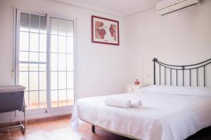 una camera bianca con un letto e una grande finestra di Dúplex Completo La Manga dos playas a La Manga del Mar Menor