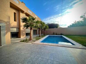 a swimming pool in front of a building with palm trees at MARRAKECH , Ourika in Ourika