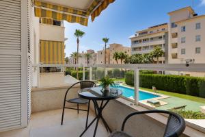 a balcony with a table and chairs and a pool at Apartamentos Oasis in Albir