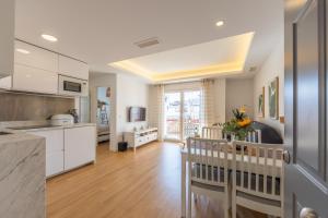 een keuken en een woonkamer met witte kasten bij Central but quiet, pool and WIFI - fibre in Tarifa