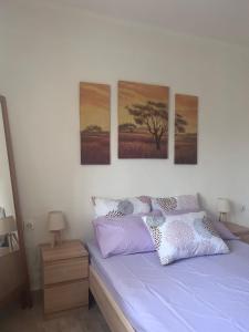 a bedroom with a bed with four paintings on the wall at Beverly house in Kriopigi