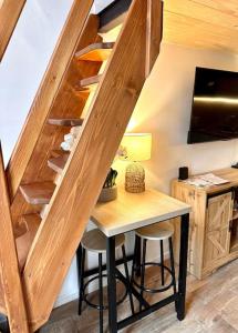 a wooden staircase with a table and stools in a room at Jungle avec Jaccuzi au coeur de Nice in Nice