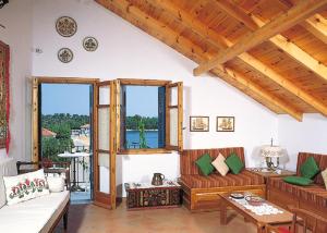 a living room with couches and a table and windows at Vassili's Apartment, Kefalonia in Fiskardo +1 photo
