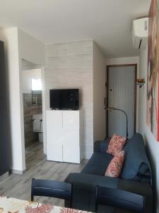 a living room with a blue couch and a television at Comfy flat with terrace by the pool in Rosolina Mare +21 photos