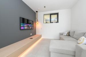 a living room with a couch and a tv at MGH Luxury - Corte Garden Bardolino 34 in Bardolino