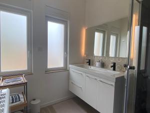 a white bathroom with a sink and a mirror at La musique des Vacances in Portbail +43 photos