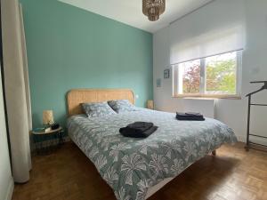 a bedroom with a bed with a green bedspread and a window at La musique des Vacances in Portbail