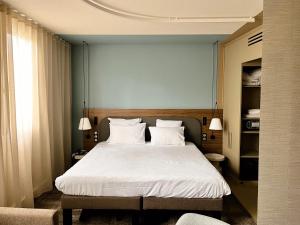 a bedroom with a large bed with white sheets and pillows at Novotel Suites Clermont Ferrand Polydome in Clermont-Ferrand