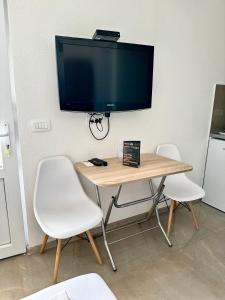 a table with two chairs and a television on a wall at Montenegrina Apartment in Budva