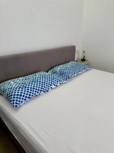 a bed with a blue and white pillow on it at Montenegrina Apartment in Budva