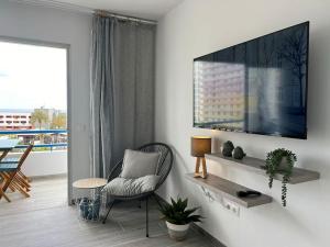 een woonkamer met een stoel en een televisie aan de muur bij Playa Paraiso Apartment in Adeje