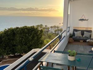 een balkon met een tafel en een bank en de oceaan bij Playa Paraiso Apartment in Adeje