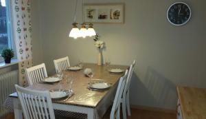 een eettafel met witte stoelen en een klok bij Villa Tall in Vidsel