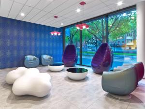 una sala de espera con sillas moradas y una gran ventana en Prize by Radisson, Hannover City, en Hannover