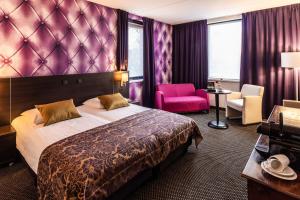 a hotel room with a bed and a pink chair at Fletcher Hotel-Restaurant Zevenbergen-Moerdijk in Zevenbergen