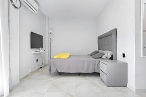 Un dormitorio blanco con una cama y un televisor. en @SeaFront, en Sitio de Calahonda