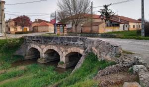 an old stone bridge over a river in a town at Casa rural ‘’La Nuestra’’ in Bercimuel