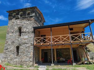 an old stone building with a tower with a balcony at Chazhashi Guesthouse - Rooms with Private Bathrooms in Ushguli