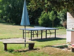 Una mesa de ping pong con una sombrilla y un banco. en Ferienhaus Riebe, en Stollhamm