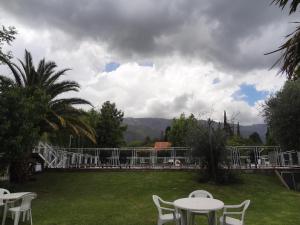 eine Terrasse mit weißen Tischen und Stühlen im Hof in der Unterkunft Hostería Lida in Merlo