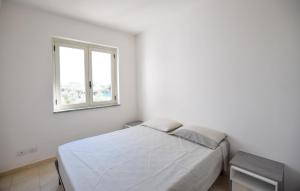 Awesome Apartment In Isca Marina في بادولاتو: غرفة نوم بيضاء مع سرير ونافذة