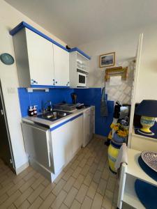 a kitchen with blue walls and white cabinets and a sink at T2 Mer et Soleil avec Terrasse in Sète +9 photos