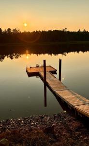 a dock on a lake with the sunset in the background at The Hideaway Cottage with Private trails in Waweig