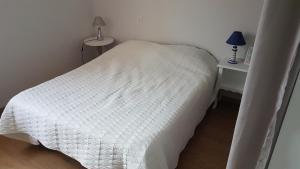 a small bedroom with a white bed and a table at maison proche du lac in Aureilhan