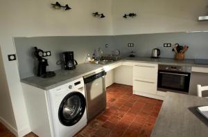 a kitchen with a washing machine and a sink at La charmille in Saint-Gaudens