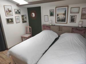 a bedroom with a bed with white sheets and pictures on the wall at Gîte de la haute roche in Charroux