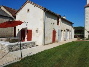 a white building with red doors and an umbrella at Le studio de saint-maixent le petit in Haims