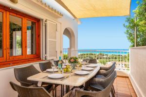 uma mesa e cadeiras num pátio com vista para o oceano em Villa Caterina by Villa Plus em Alaior