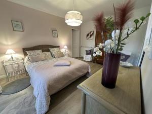 una camera da letto con un letto e un vaso su un tavolo di Gite des graverots ad Aire-sur-lʼAdour