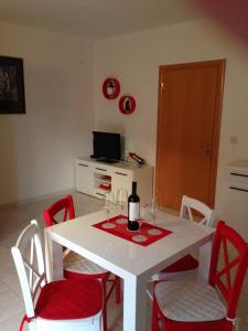 a white table with red chairs and a bottle of wine at Villa Jasmin in Bol