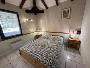 a bedroom with a bed and two tables and a window at Peyrot in Onesse-et-Laharie