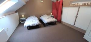 an attic room with two beds and red curtains at L'envol in Fumay