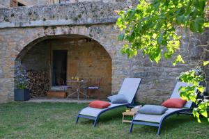 two chairs and a table in front of a stone wall at Gîte La Lauze de Marijoulet 2/4 personnes in Chanac
